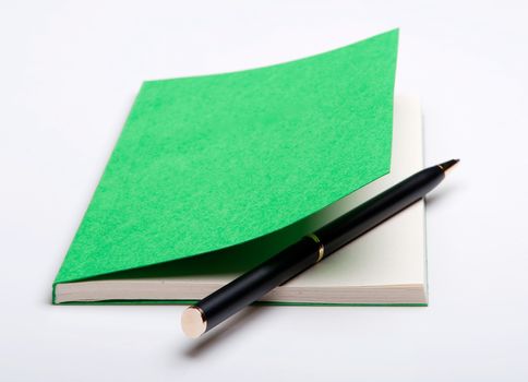 Isolated close-up of a ballpoint pen in a notepad on the white background