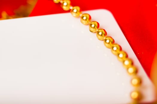 Gold beads and white card on red cloth. macro shooting
