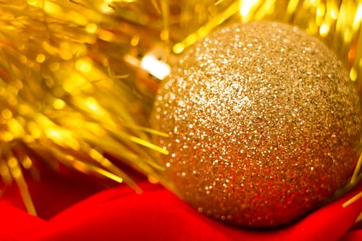 Christmas golden ball and tinsel on red fabric. macro