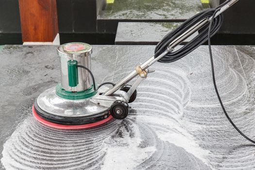 Thai people cleaning black granite floor with machine and chemical