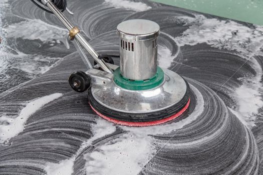 Thai people cleaning black granite floor with machine and chemical