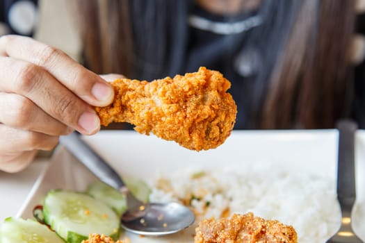 Hand holding Fried chicken and eating in the restaurant