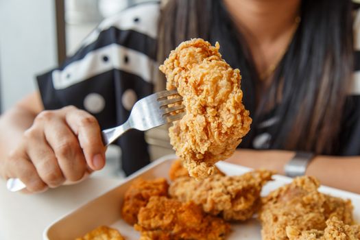 Hand holding Fried chicken and eating in the restaurant