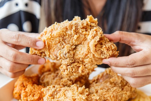 Hand holding Fried chicken and eating in the restaurant