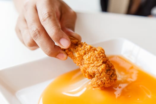 Hand holding Fried chicken and eating in the restaurant