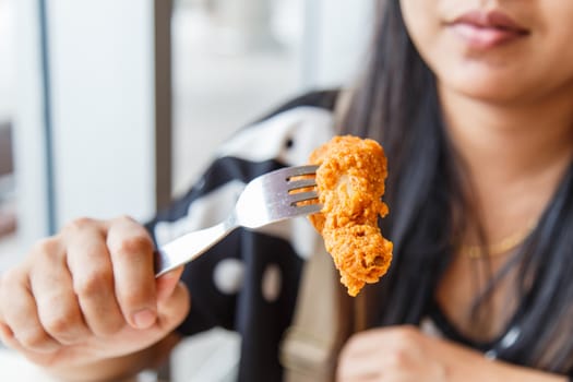 Hand holding Fried chicken and eating in the restaurant