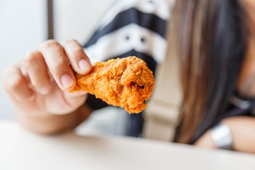Hand holding Fried chicken and eating in the restaurant