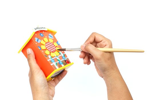 Hand holding paintbrush and painting isolated on white background