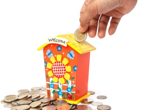 Hand holding coin and put in piggy bank isolated on white background