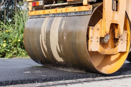 Road roller and asphalt paving machine at construction site