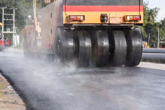 Road roller and asphalt paving machine at construction site