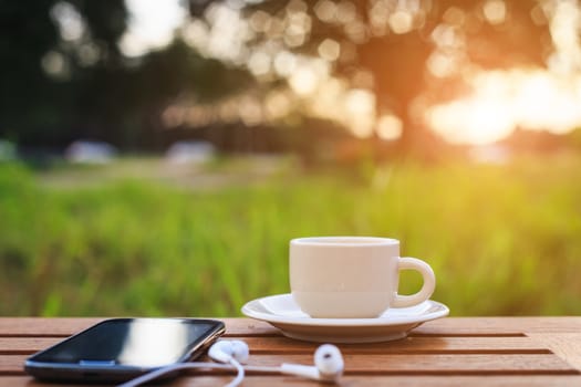 Coffee cup and smartphone on the table in sunset time