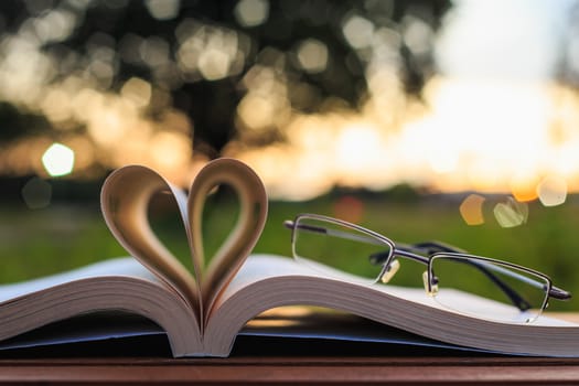 Close up book and glasses on table in sunset time