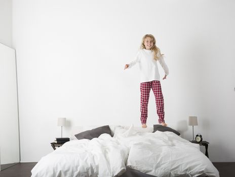 Happy Little Girl Jumping in bed with a smile on her face