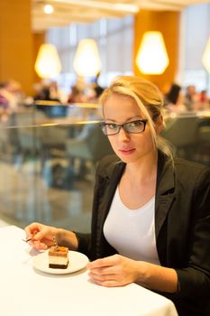 Business woman eating her favorite dessert in a fancy modern hotel restaurant. Unable to resist our sweet vices. Lifestyles.