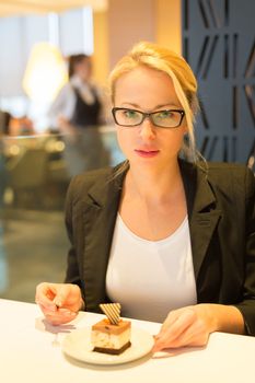 Business woman eating her favorite dessert in a fancy modern hotel restaurant. Unable to resist our sweet vices. Lifestyles.