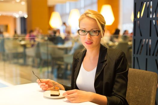 Business woman eating her favorite dessert in a fancy modern hotel restaurant. Unable to resist our sweet vices. Lifestyles.