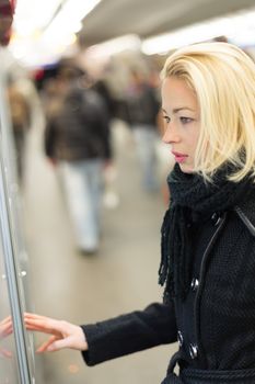 Casually dressed woman wearing winter coat,buying metro ticket at the ticket vending machine. Urban transport.