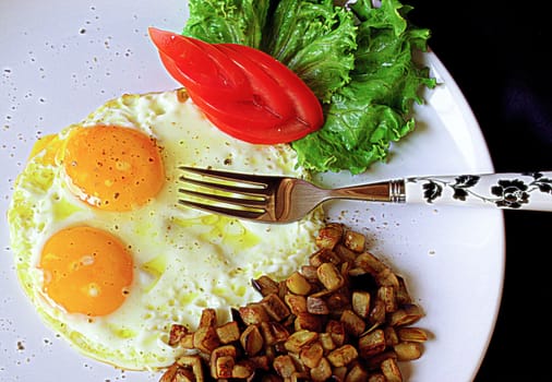 Fried eggs and vegetarian garnish on white plate with fork