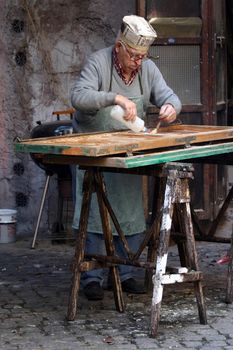 Old fashioned joiner applies some liquid filler on a window door