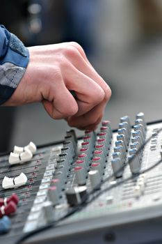 Man's hand is tuning some settings on mixer keyboard