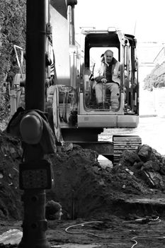 Two workers digging a hole with excavator in yard