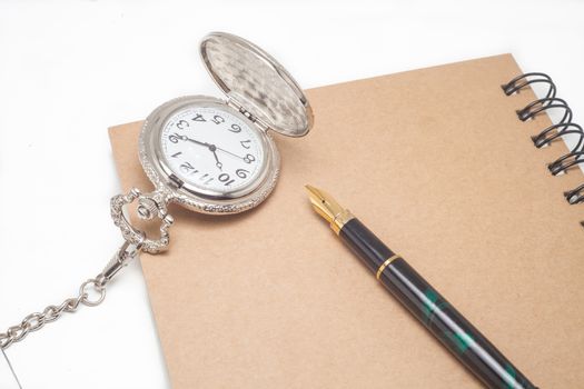 fountain pen and pocketwatch on book