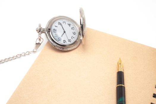 fountain pen and pocketwatch on book