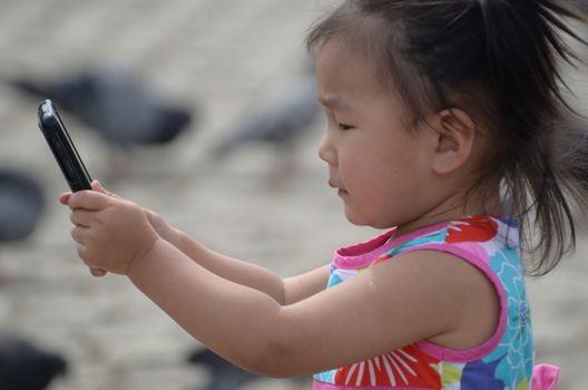 Korean baby girl watches smartphone with interest