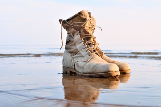 Yellow boots with a shoelaces on a wet sandy beach