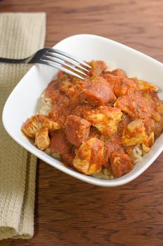 Jambalaya in a white bowl on a wooden table.