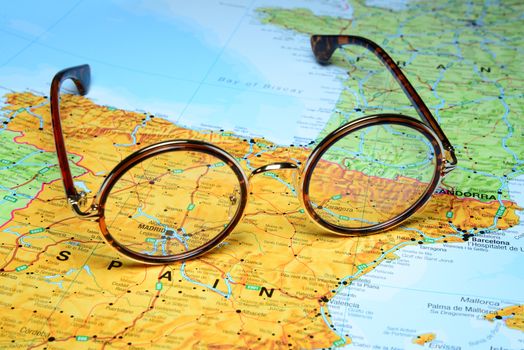 Photo of glasses on a map of europe. Focus on Madrid, Spain. May be used as illustration for traveling theme.