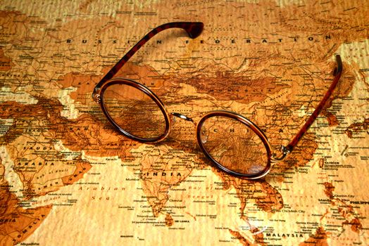 Photo of glasses on a map of a world, antique style. Focus on China. May be used as illustration for traveling theme.