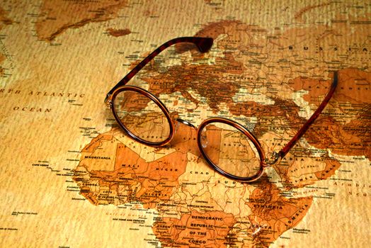 Photo of glasses on a map of a world, antique style. Focus on Egypt. May be used as illustration for traveling theme.