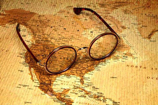 Photo of glasses on a map of a world, antique style. Focus on United States. May be used as illustration for traveling theme.