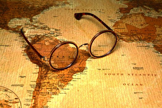 Photo of glasses on a map of a world, antique style. Focus on Brazil. May be used as illustration for traveling theme.