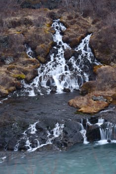 late winter at hraunfossar waterfall, a flow through lava rock