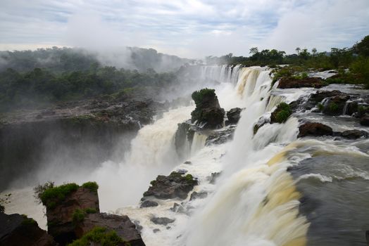 Iguazu waterfall in south americal tropical jungle with a massive flow of water