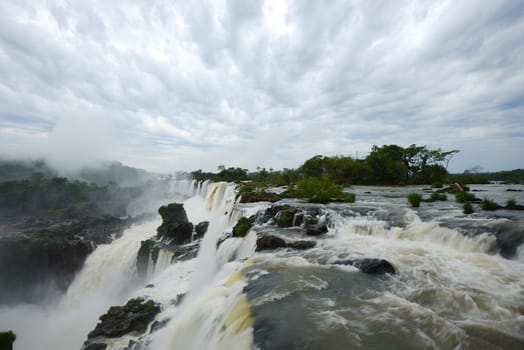 Iguazu waterfall in south americal tropical jungle with a massive flow of water