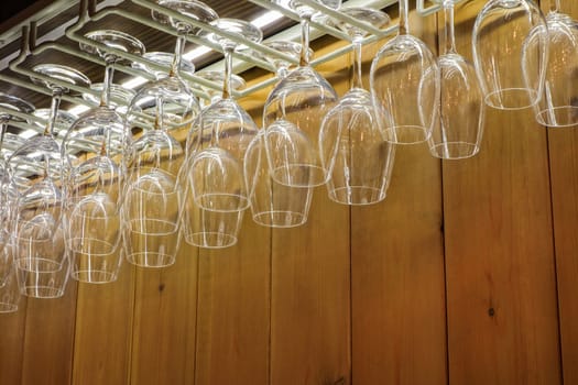 Many wine glasses hanging above the bar in a nightclub