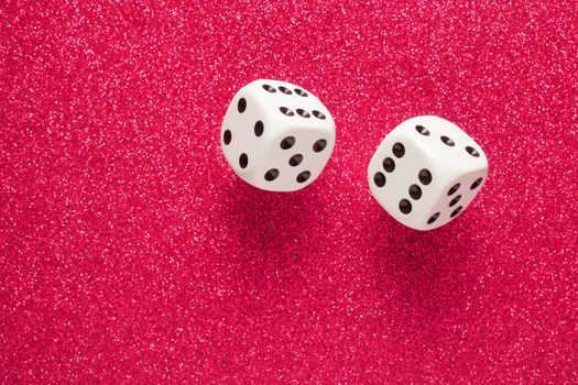 Rolling white dice over red glittering surface