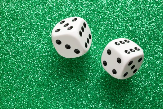 Rolling white dice over green glittering surface