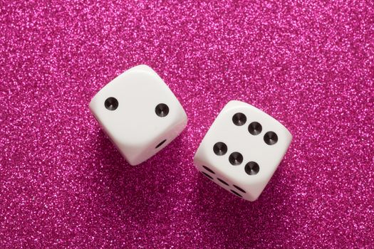 Rolling white dice over purple glittering surface