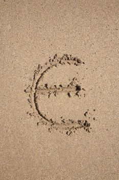 Euro symbol written on brown sand ground low tide beach ocean seashore in Spain Europe