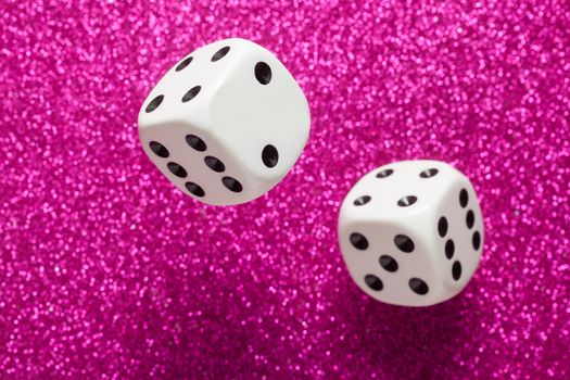 Rolling white dice over purple glittering surface