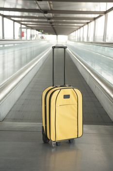 lonely yellow suitcase with black handle at walkway inside airport hall