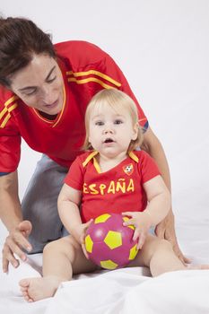 surprised face blonde baby sixteen month old with red shirt of Spanish soccer team and mother