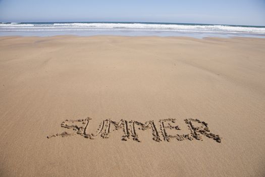 summer word written on brown sand ground low tide beach ocean seashore in Spain Europe