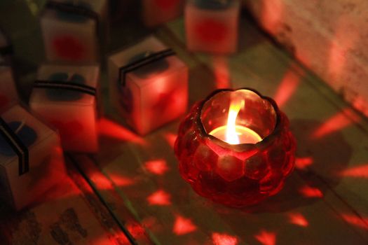 Sweet candle is lighting in a red jar. Romantic light shine.