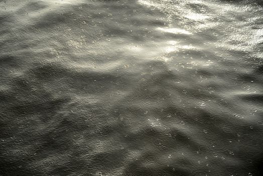 Photo of a water surface with rain drops and sunlight reflection. Taken in Riga, Latvia